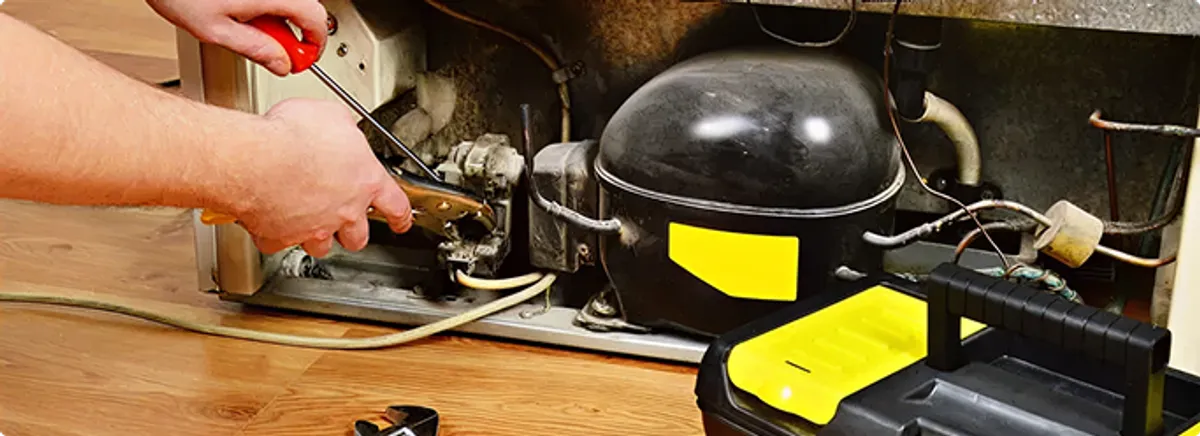 Refrigerator repair technician fixing the compressor and wiring in Clive, IA